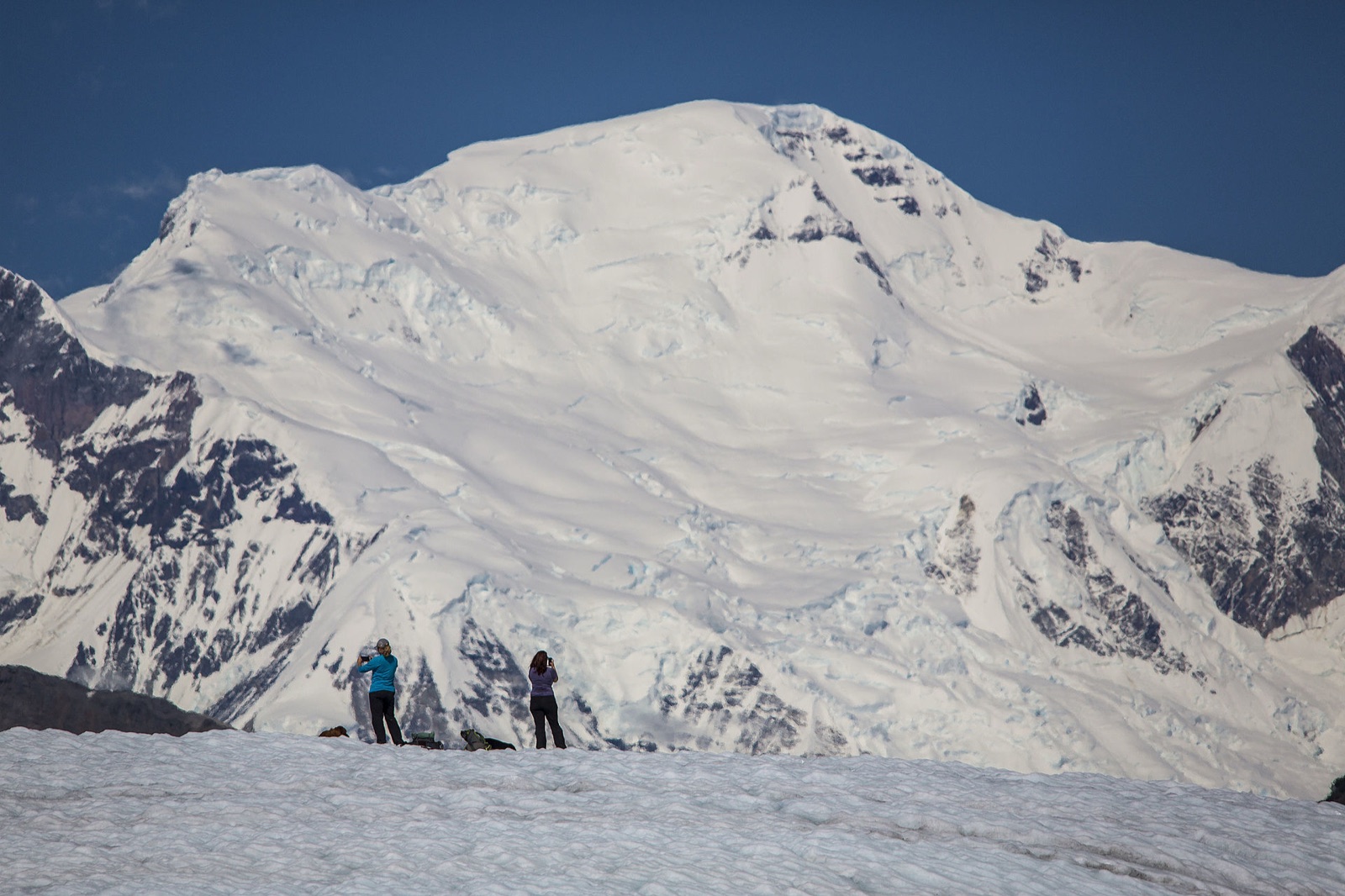 Mujeres caminando en glaciar contra montaña masiva